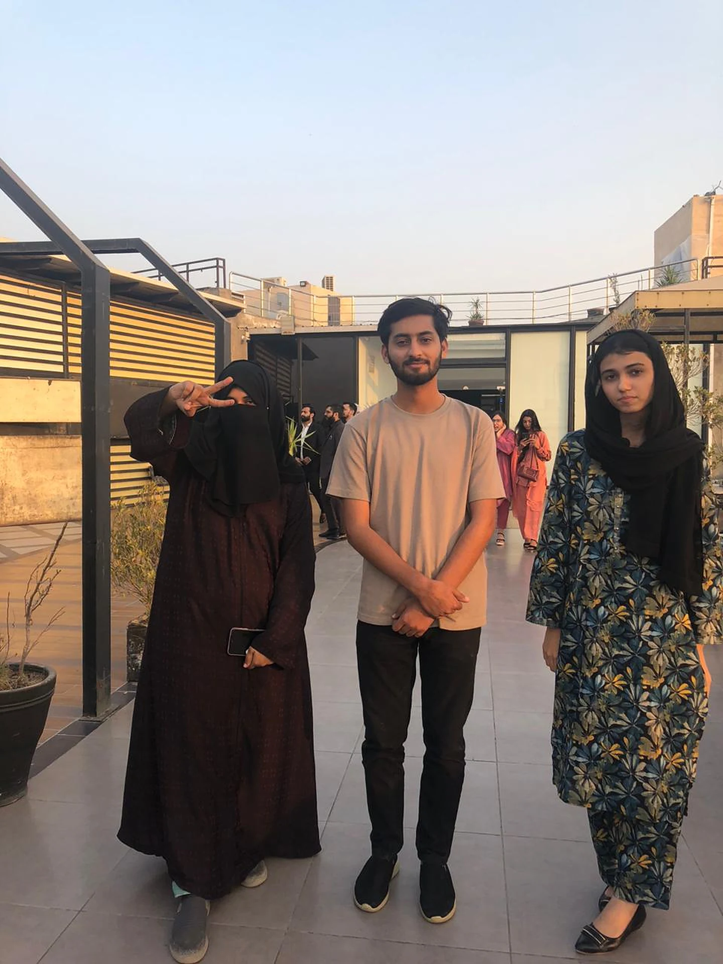 Three attendees standing together at an outdoor rooftop gathering.