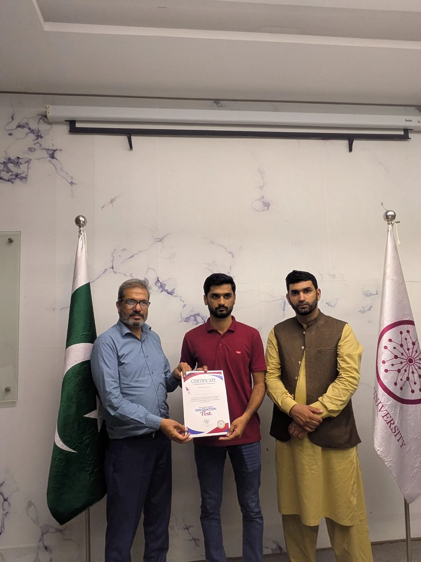 A certificate being presented during a formal photo between three people.