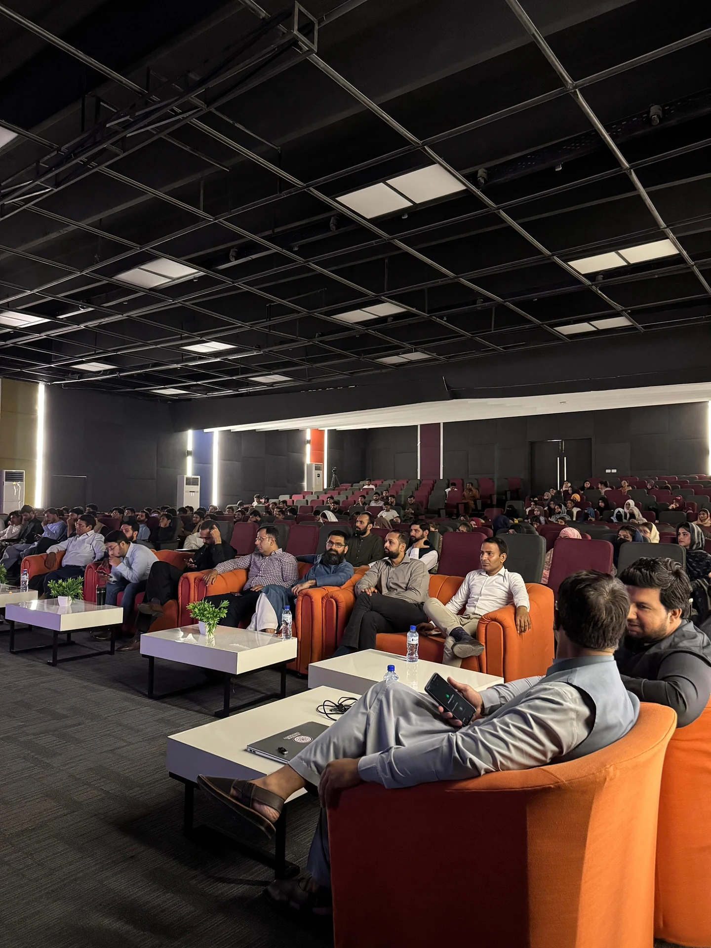 A side-angle view of attendees seated in an auditorium during an event.