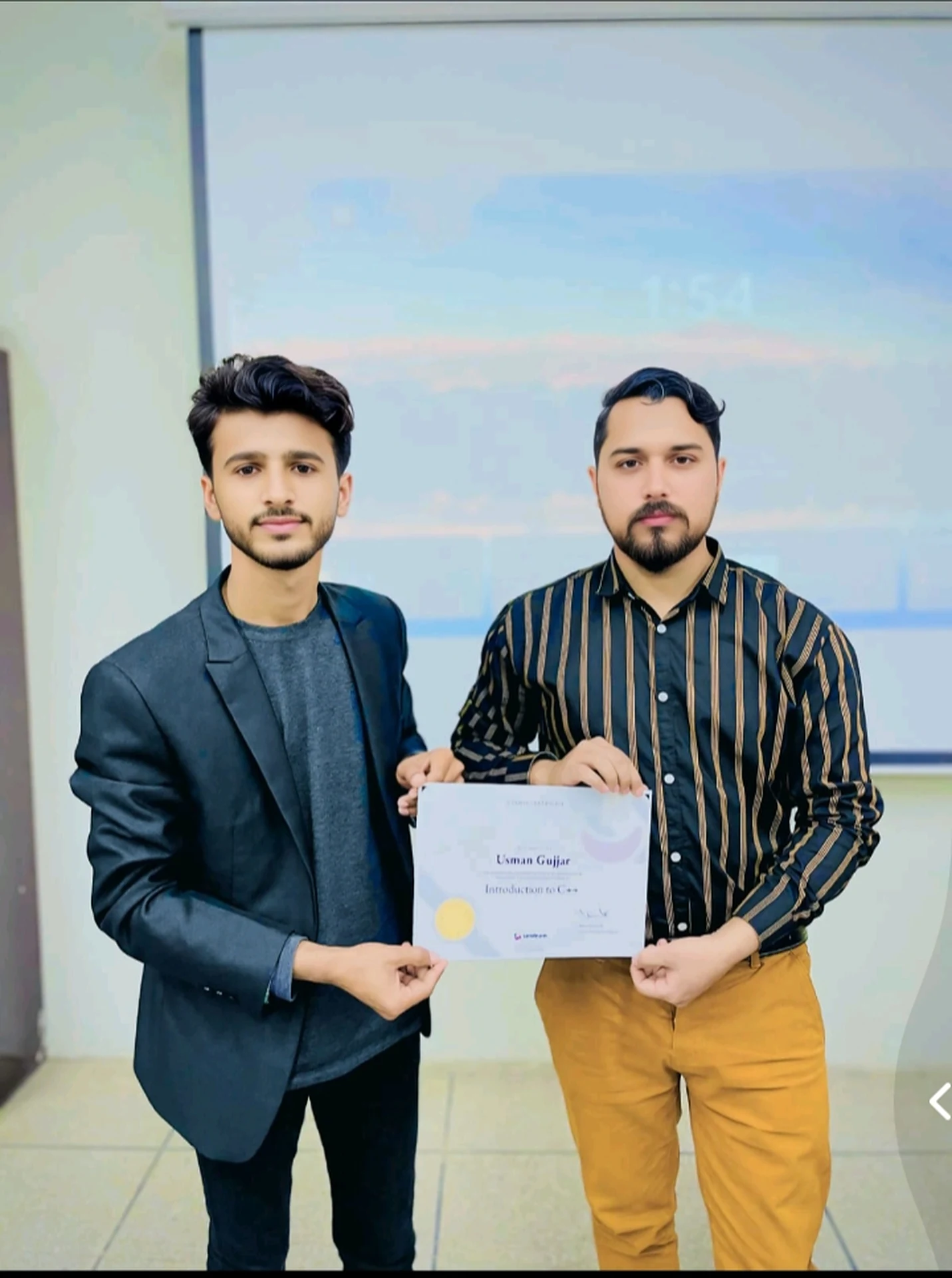 Two men holding a certificate together during a presentation.